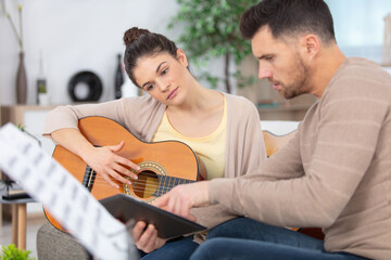 male musician teaches female student how to play the guitar