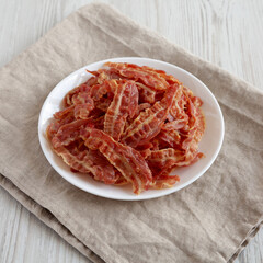 Crispy Fried Bacon on a white plate, low angle view.