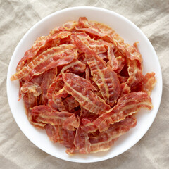 Crispy Fried Bacon on a white plate, top view. Flat lay, overhead, from above.