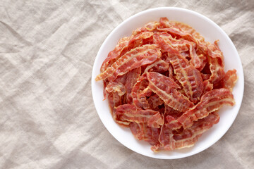 Crispy Fried Bacon on a white plate, top view. Flat lay, overhead, from above. Space for text.