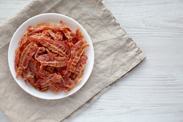 Crispy Fried Bacon on a white plate, top view. Flat lay, overhead, from above. Copy Space.