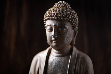 Meditating Buddha Statue on dark wooden background. Close up. Copy space.	