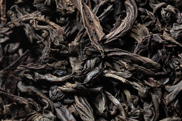 Dried black tea leaves as background.