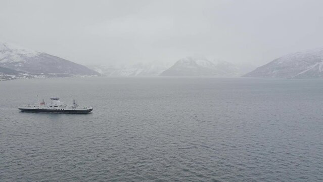 Ferry between Olderdalen and Lyngseidet in Kåfjord, Norway. Overcast winter fog. 
Ferry moves from left to right. 4k drone shot.