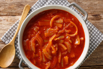 Homemade onion sauce with tomatoes, garlic and spices close-up in a saucepan on the table. horizontal top view from above