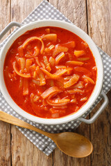 Cebolada is a Portuguese onion stew, onion sauce or paste that is prepared with onion as a primary ingredient close-up in the pot on a wooden table. Vertical top view from above