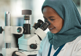 Conducting fair tests. Shot of a young scientist using a microscope in a lab.