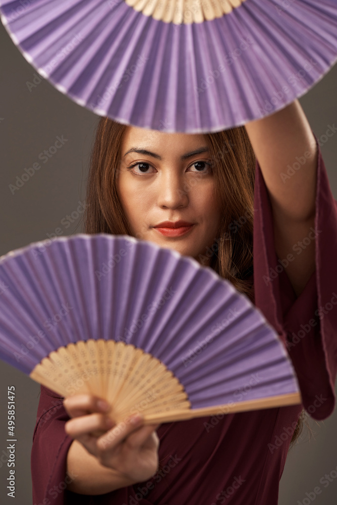 Poster Whats behind your heritage. Cropped portrait of an attractive young woman posing with fans in studio against a grey background.