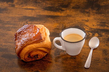 cup of coffee and croissant on wooden background