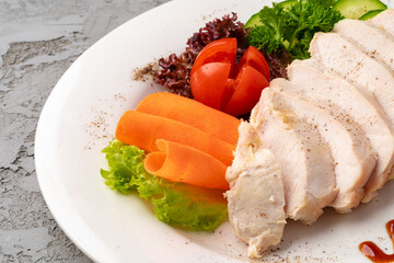 Roast chicken fillets and vegetables on gray background