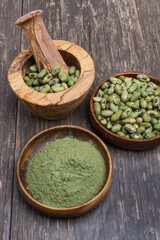 supergreens powder and green beans in a mortar and whisk. On a wooden table.