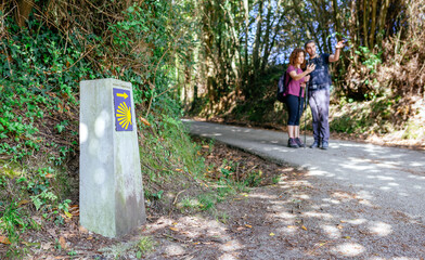 Signpost of Saint James way with pilgrims pointing the path in the background - obrazy, fototapety, plakaty