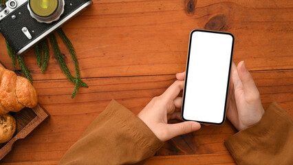 Female blogger sit in a cafe and using smartphone over wooden table.