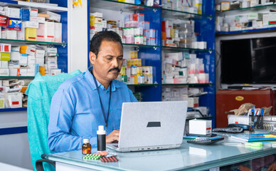 handheld shot Pharmacist working on laptop retail medical shop - concept of technology, checking or making new orders or medicine stocks and small businesses.
