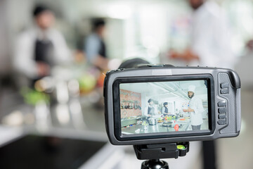 Close up of camera recording food industry workers cooking delicious vegetable gourmet dish in restaurant kitchen. Gastronomy experts broadcasting meal preparing process for TV culinary show program.