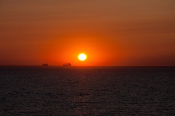 sundown sky and sea with ship on horizon, summer