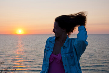 happy young lady look at summer sunset sun and sky with seascape