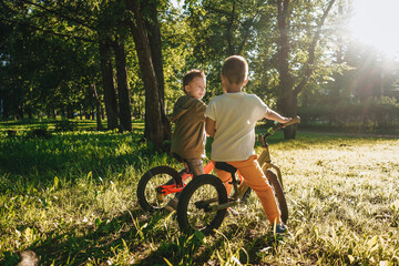 Two boys riding balance bikes in park.