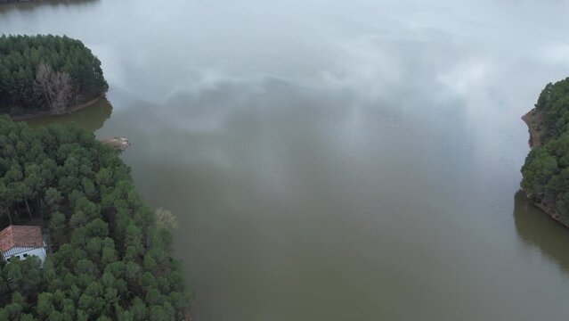 Aerial drone view of a medium size dam and a reservoir in a cludy day over mirrow water, in Castellon, Spain