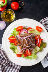Vegetable meat salad in a plate against a dark background. Selective focus. Top view. Copy space