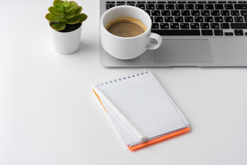 Office desk with laptop, blank notebook and coffee cup