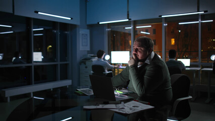 Overweight stressed manager work late on laptop in office