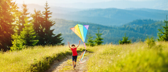 Little happy child boy running with kite. Wonderful mountain landscape in Alps at sunset. Travel, vacation alps. - obrazy, fototapety, plakaty