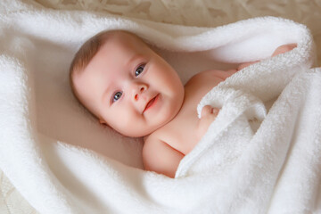 baby is wearing diapers and a white towel in bedroom. top view . A newborn baby is resting in bed after a bath or shower. Children's room. Textiles and bedding for children