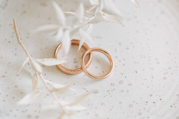 Eheringe in Rotgold auf einem weißen Teller mit Trockenblumen, Hochzeitsdekoration 