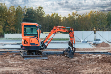 Mini excavator at the construction site. Compact construction equipment for earthworks.