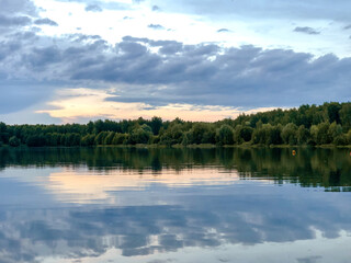 Summer forest lake with clouds reflected in water landscape