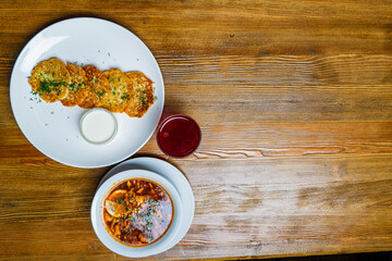 Pieces of chop (schnitzel), toast with eggs, fresh tomato on a wooden board on a dark background. Top view.