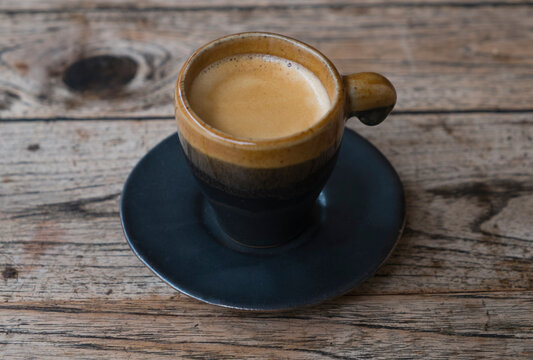 Coffee in espresso cup and saucer on wooden table