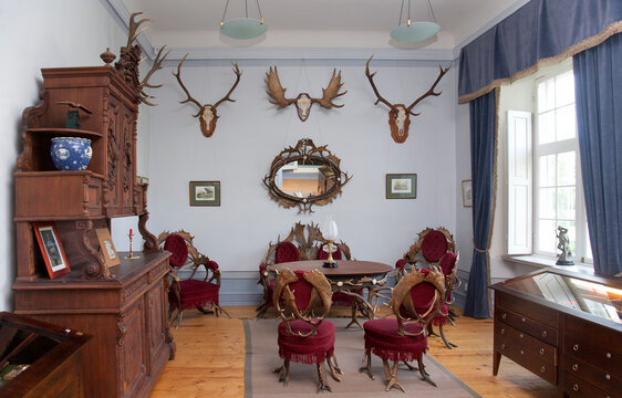 Traditional furniture and hunting trophies, carved chest of drawers, wall plaques and chairs and table made from deer antlers. 