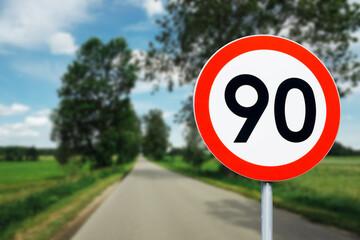 Speed limit sign with trees behind. Maximum ninety kilometers per hour. Safety on road background. White round sign red border line. Traffic ticket background. Speeding fine. - obrazy, fototapety, plakaty