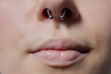 Closeup of a young woman's visage with piercing septum hanging from her nose. - obrazy, fototapety, plakaty