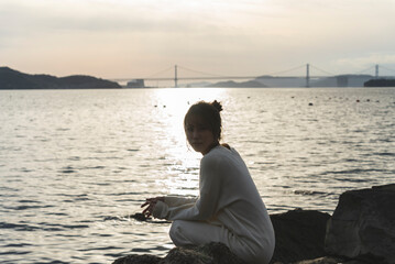 夕暮れの海岸線を歩く女性