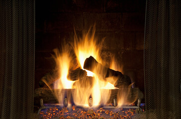 A domestic fireplace, hearth, fire lit, logs and flames. 
