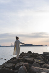夕暮れの海岸線を歩く女性