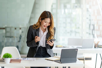 Happy Young Asian Business Woman Successful Excited Raised Hands Rejoicing With Smartphone.