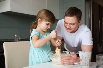 family time together. Dad and little daughter make pie dough together in the kitchen of the house