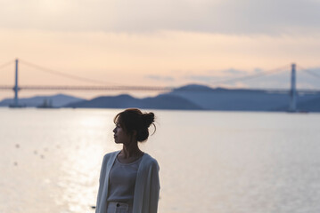 夕暮れの海岸線を歩く女性