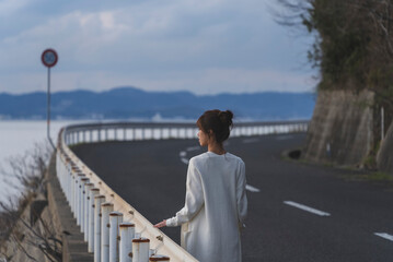 夕暮れの海岸線を歩く女性