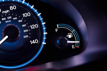 A car interior, the dashboard,instrument panel,and fuel gauge. A speedometer.