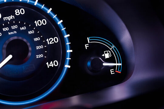 A car interior, the dashboard,instrument panel,and fuel gauge. A speedometer.