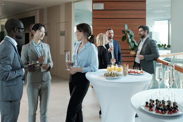 Young intercultural entrepreneurs with champagne discussing best reports after conference while...