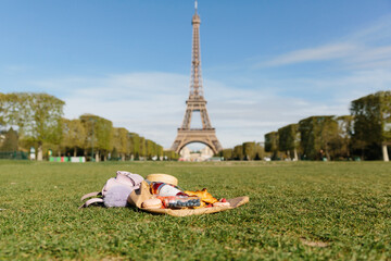 Landscape of Eiffel Tower on blue sky background. Selective focus on picnic with wine and berries...