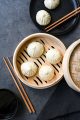 Xiao long bao or baozi dumplings in   bamboo steamers,  chopsticks and bowl of sauce. Chinese food delivery