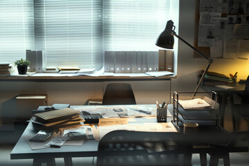 Lamp lighting workplace of contemporary FBI agent with criminal profiles, stacks of journals,...