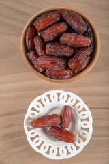Date fruit in bowl on wooden background, top view